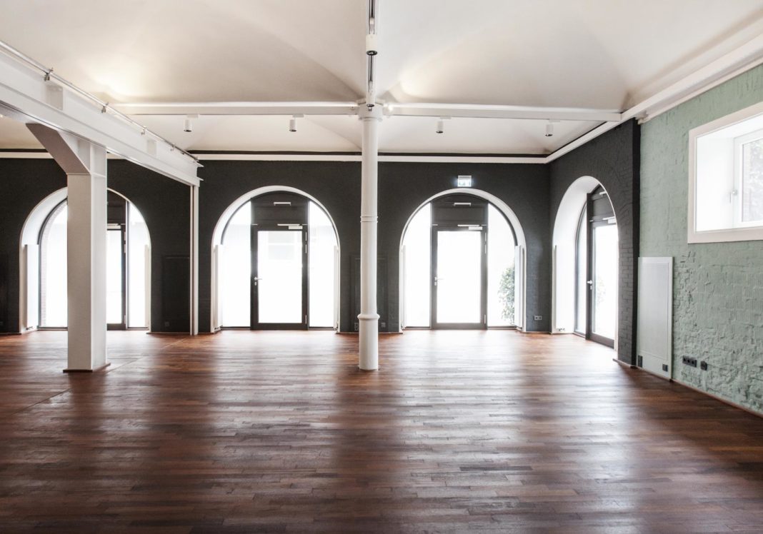 großer raum mit holzboden und bogenfenstern mosaique lüneburg innenausbau formwaende